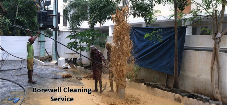 Provide a borewell cleaning service, two employees clean a borewell, causing muck & water to splash.