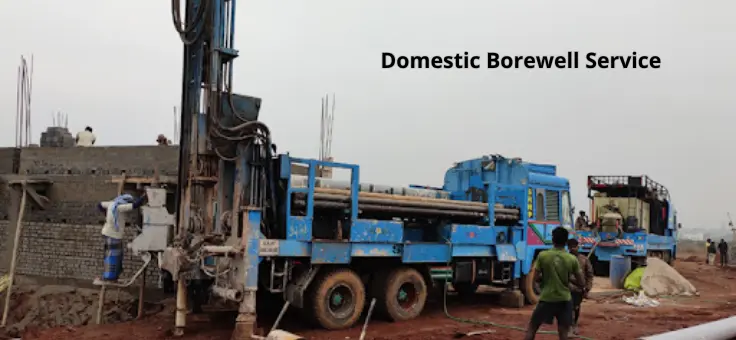 A man is standing next to a massive motor vehicle that belongs to domestic borewell engineers.