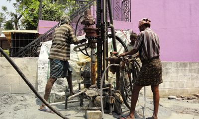 Two people using heavy borewell equipment for 4.5 borewell drilling services for domestic needs.