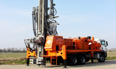 A large orange truck prepared for borewell drilling services, including drilling equipment.